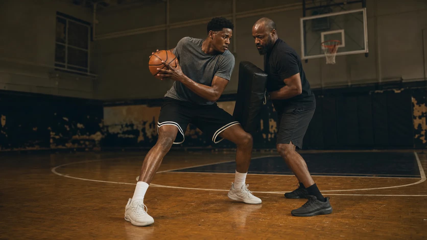 A post player protecting the ball while practicing pivot footwork against a contact pad